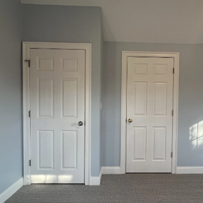 Freshly painted white interior door and trim in a carpeted room with light gray walls