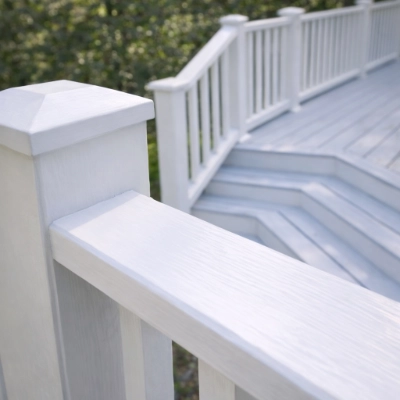 Close-up of restored exterior wooden deck stairs and railing painted with premium white coating