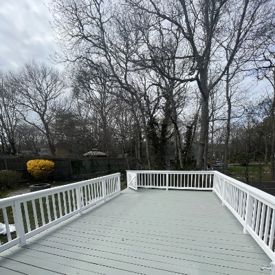 Large coastal wooden deck with white railings freshly restored in Cape Cod