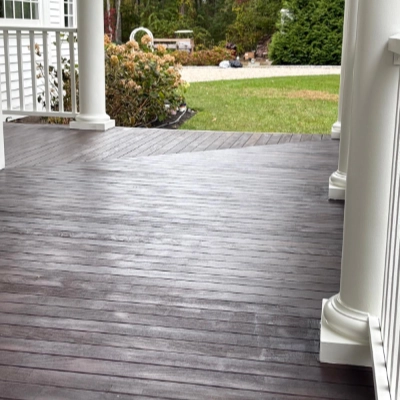Refinished dark wood exterior porch flooring next to white pillars
