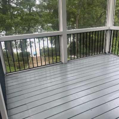 Covered coastal porch with newly painted light gray deck flooring and black railings