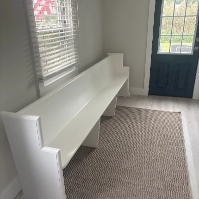 Custom built long white wooden bench painted in a bright entryway