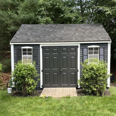 Close-up of a freshly painted vibrant turquoise exterior window shutter against weathered coastal wood siding