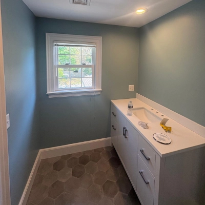 Freshly painted bathroom with teal walls, a white vanity, and hexagonal floor tiles