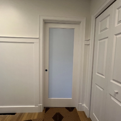 Bright living space with light neutral walls, crisp white window trims, and a vaulted ceiling