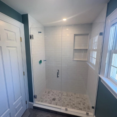 Bathroom featuring dark teal painted walls, crisp white trim, and a glass-enclosed subway tile shower