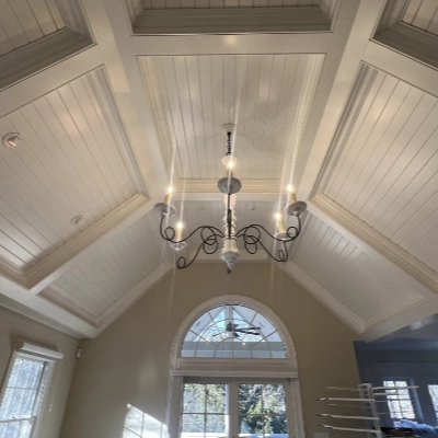 High vaulted ceiling with perfectly painted white beadboard paneling and a chandelier