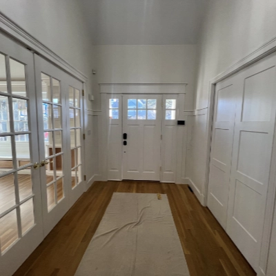 Bright entryway hallway with crisp white painted doors, wainscoting, and hardwood floors