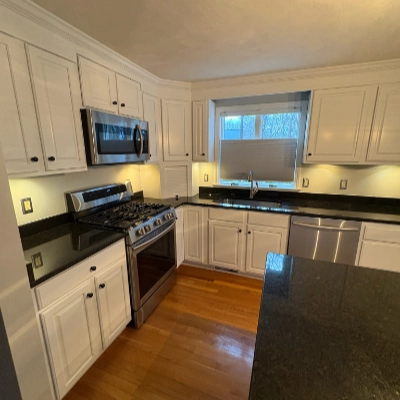 Kitchen with freshly refinished white cabinets, dark countertops, and stainless steel appliances