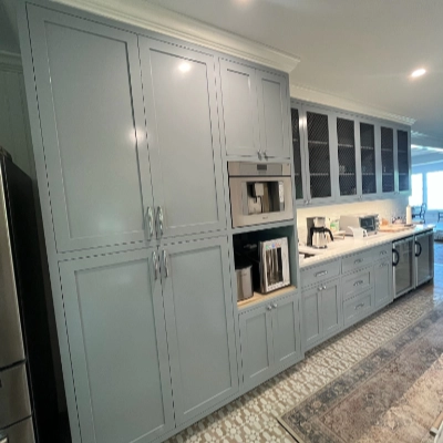 Floor-to-ceiling kitchen cabinets painted in a soft gray blue tone with built-in appliances