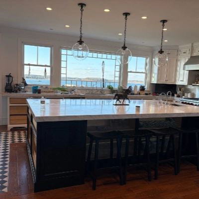 Black refinished kitchen island with marble top and coastal ocean view in the background