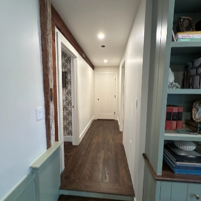 Built-in hallway bookshelf and cabinetry painted in a soft sage green finish