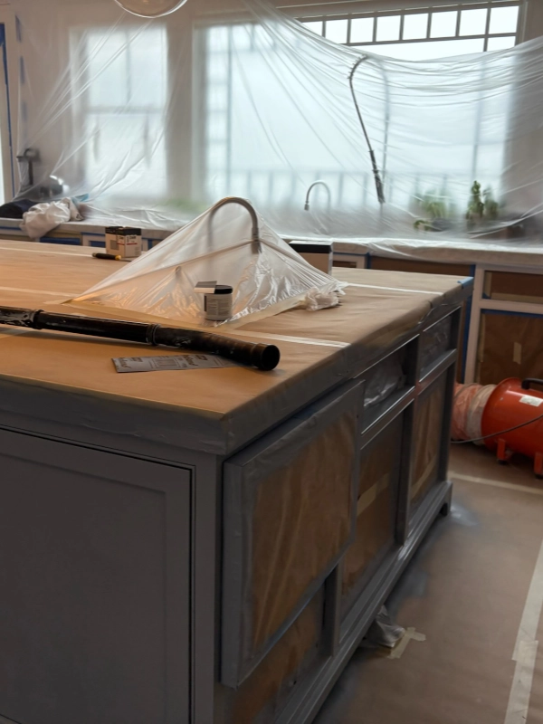 Kitchen island completely sealed with protective plastic sheets and masking paper before painting