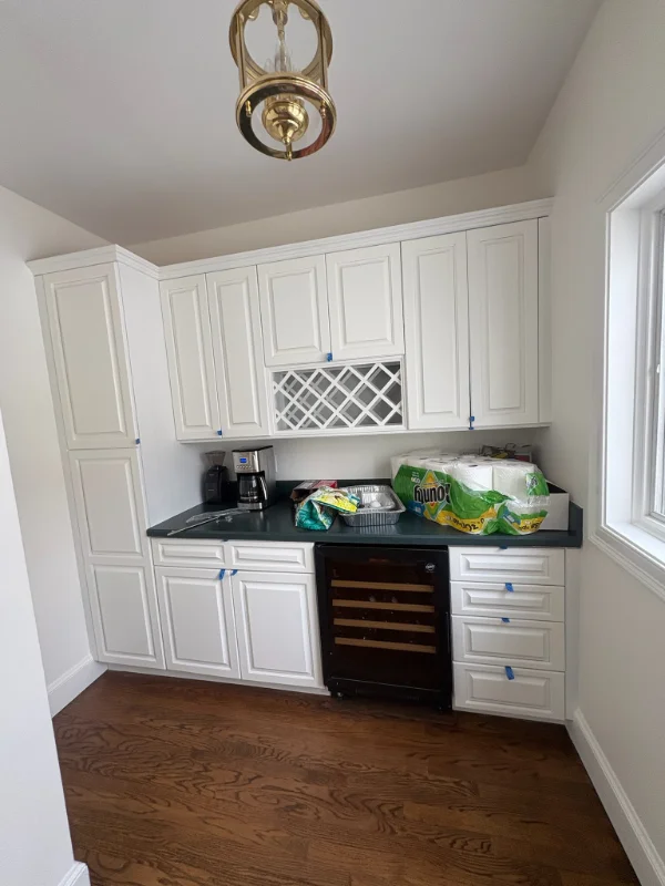 Beautifully restored bright white kitchen cabinets featuring a built-in wine rack and dark countertops